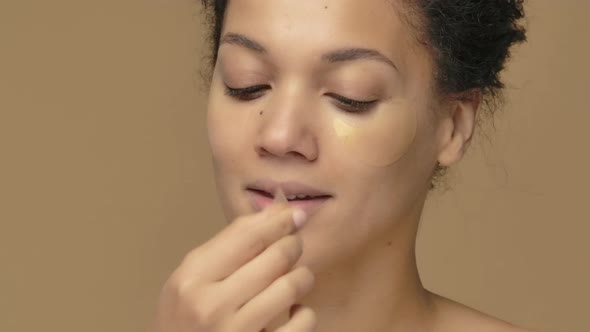 Beauty Portrait of Young African American Woman Removes Eye Gold Patches Under Eyes for Fresher Look
