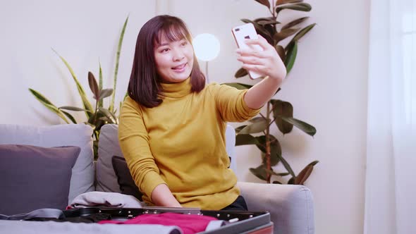 Asian woman taking selfie while preparing for travel.