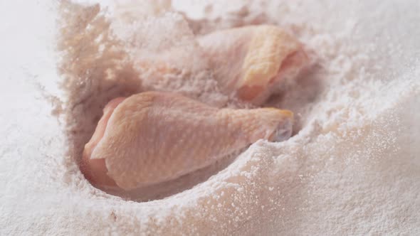 Fresh raw chicken drum dropped into flour. Slow Motion.