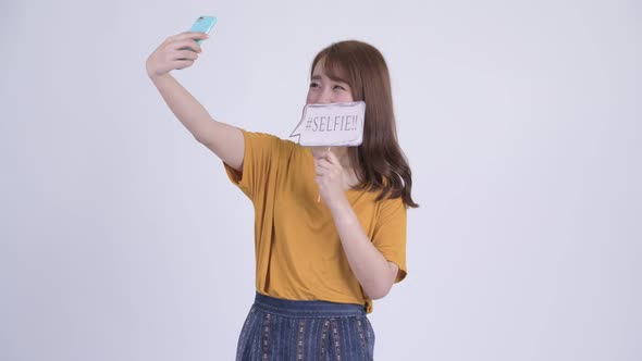 Happy Young Beautiful Asian Woman Taking Selfie with Paper Sign