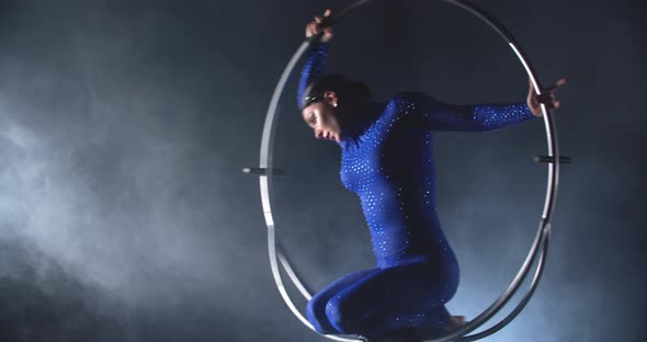 Young Woman in Blue Costume is Spinning in a Hoop Gymnastics Show