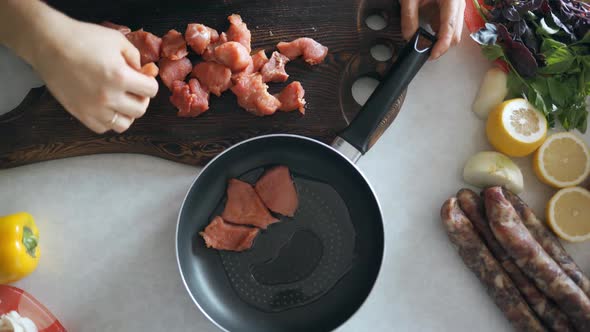 Hands of Chef Cooks Meat in a Frying Pan