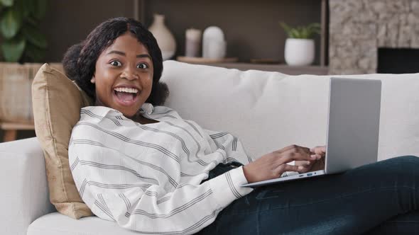 African Girl Student Woman Freelancer with Laptop Lying on Sofa Getting Good News Offer Positive