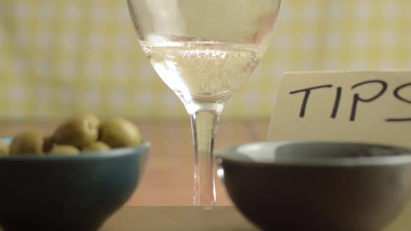 Tipping jar in cafe with white wine pouring in background close up shot