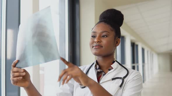 Female African American Doctor or Intern Examines Xray of Lungs Holding It in Hands Indoors