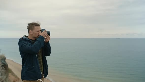 A Young Photographer on the Seashore Takes a Seascape on Camera