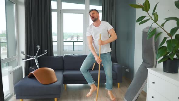 Man Cleaning the House and Having Fun Dancing and Singing with a Broom