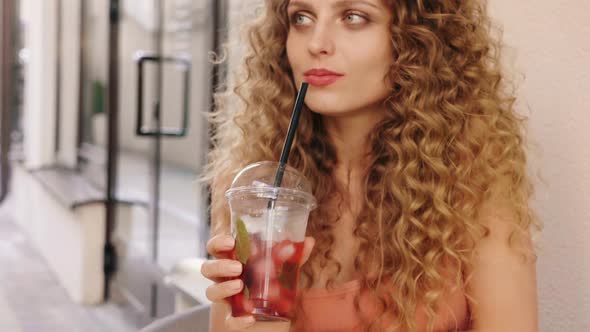 Woman in summer trendy clothes sitting in veranda cafe