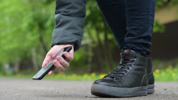 The girl finds a smartphone on the street and picks it up from the asphalt