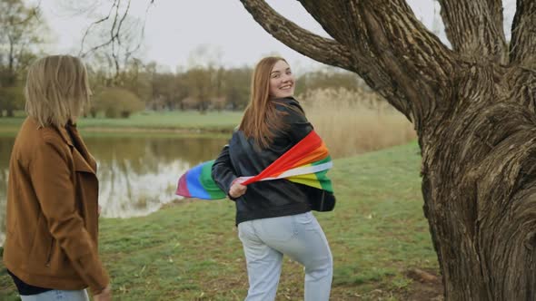 Playful Lesbian Women with Rainbow Flag Runs Away From Her Partner