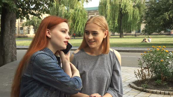 Two Girls Talking on the Same Phone