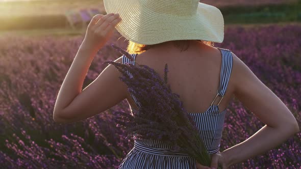 Woman in the Hat Standing in the Lavender Field at Sunset