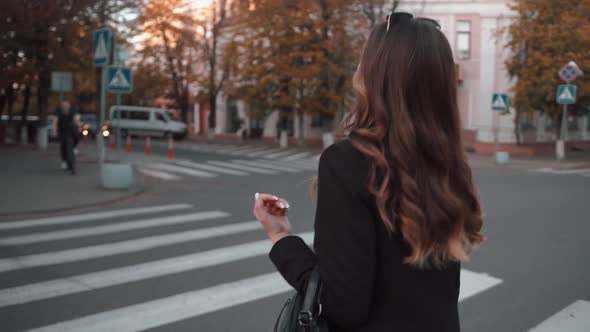 A Spectacular Young Girl Crosses the Road on Pedestrian Crossing and Turns to the Camera with Flying