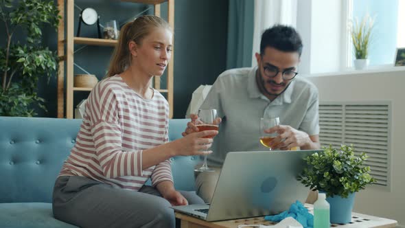 Happy Couple Clinking Glasses and Drinking Talking To Friends Online in Quarantine