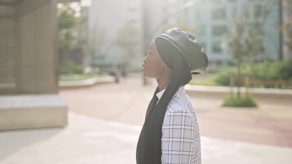 Muslim Woman Admiring Sunlit City Street