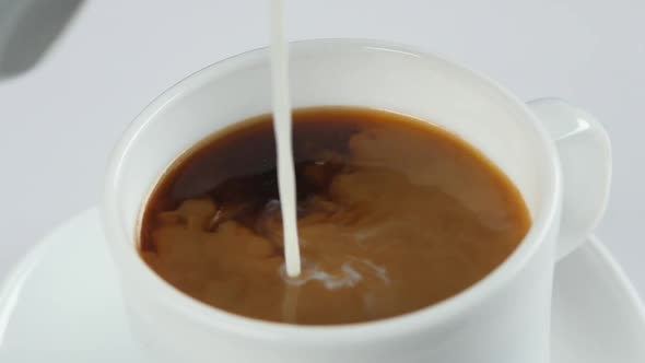 Fresh Milk Poured Into White Cup with Coffee, Slow Motion, Close Up