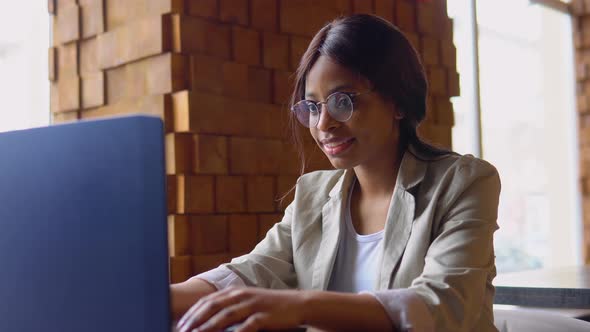 Young Indian Woman Using Laptop Computer in Cafe