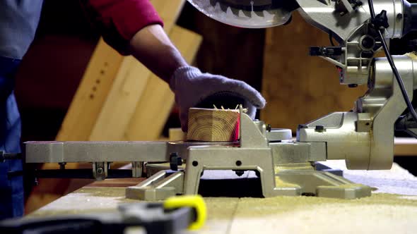 Male Carpenter Cuts Off the End of Wooden Beam Using Circular Saw with Laser