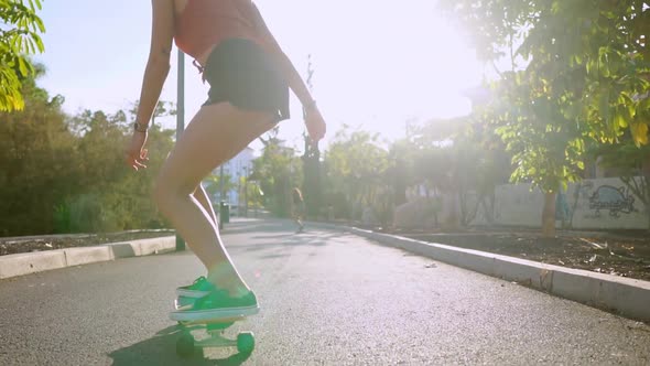 Girl in Slow Motion Rides a Skateboard in the Park with Palm Trees