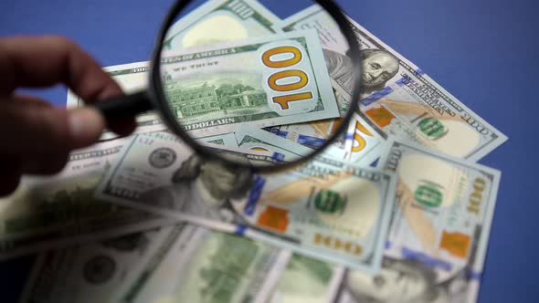 Checking 100 USD Banknotes With Magnifying Glass