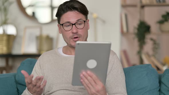 Video Call on Tablet By Middle Aged Man at Home 