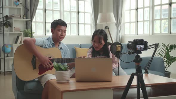 Asian Boy With Guitar And Girl Read Comment On Laptop While Streaming