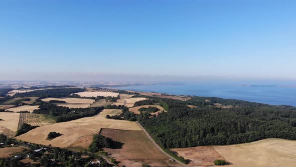 Aerial view of the coastline of Sejerøbugten with hills, fields and ocean.