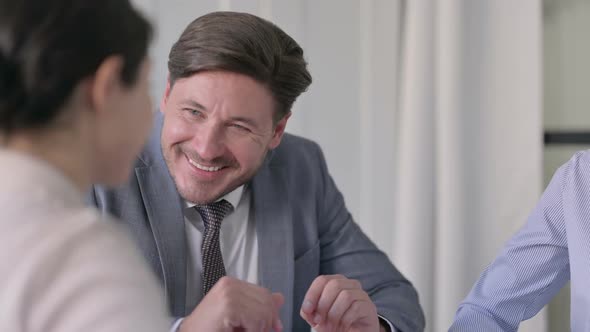 Close up of Middle Aged Businessman Talking to Female Colleagues