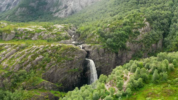 Drone Over Waterfall Cascading Into Forest Valley