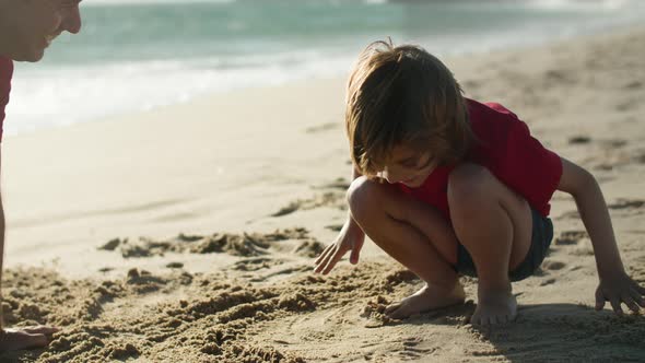 Medium Shot of Happy Father and Son Making Handprint in Sand