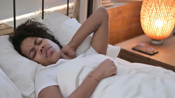 Young African Woman with Neck Pain Laying in Bed