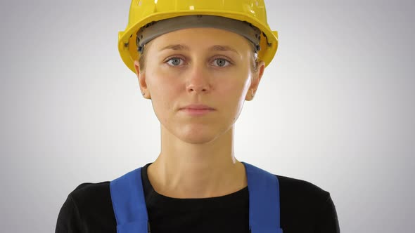 Young Attractive Caucasian Woman Builder in the Hard Yellow Helmet on Gradient Background