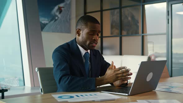 Young African American man in a suit working with a laptop in the office.