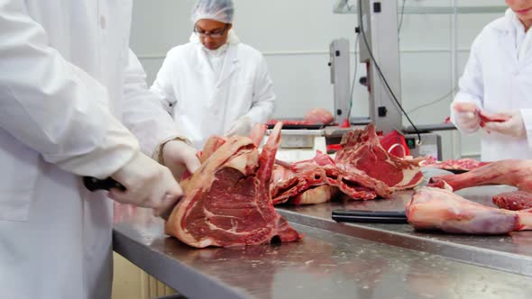 Butchers cutting meat and checking the weight of meat at meat factory