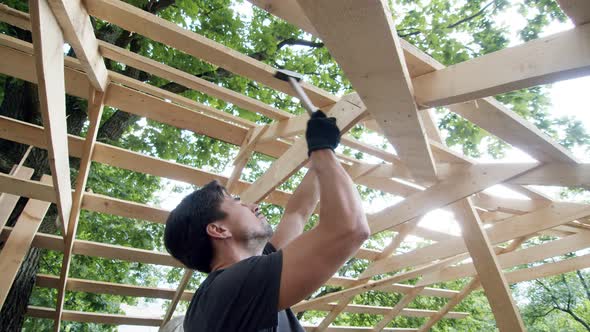 Man Hammers a Nail Into the Board