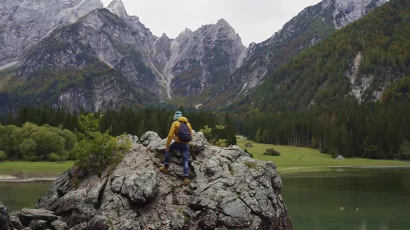 Hiker climbing on a rock at Fusine lake, Italy