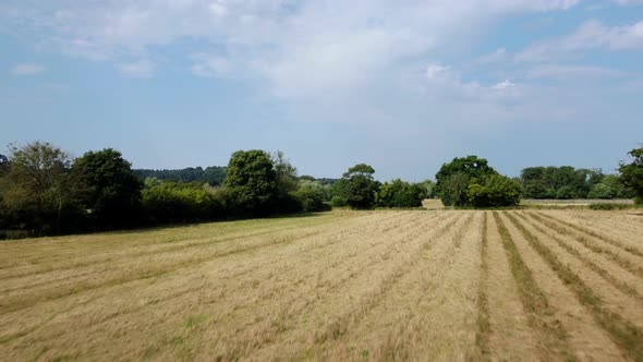 Fast drone shot flying over a farm and fields in English countryside