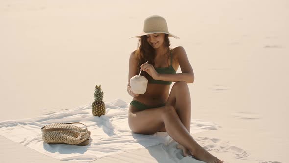 Woman with Coconut Relaxing on the Beach