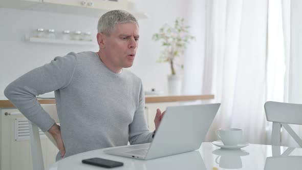 Senior Old Man with Laptop Having Back Pain at Home 