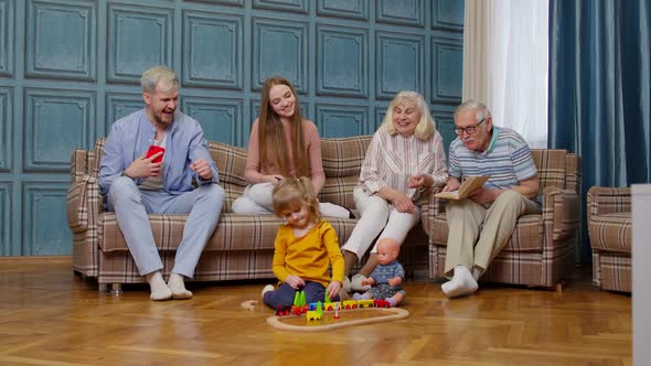 Multigenerational Family Leisure at Home Motivating Shouting to Child Kid Girl Playing Railway Toy