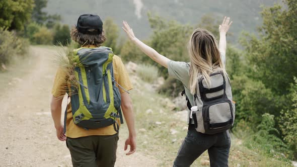 A Happy Couple Backpackers Walking By Forest's Path Rear View