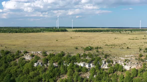 Aerial slide right, wind turbine park in green flat field