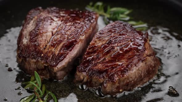 Cooking juicy meat steak with spices and herbs in pan, close up