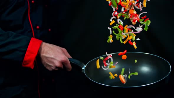 Super Slow Motion Shot of Chef Holding Frying Pan and Falling Vegetables at 1000Fps
