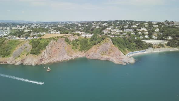 Sky view of a speed boat racing through the blue water in Torquay England. Coastline town in southwe