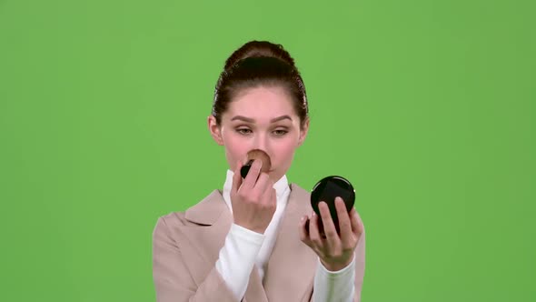 Girl Is Painted and Puts Powder with a Brush and Look in the Mirror. Green Screen