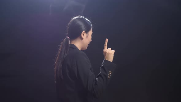 Side View Of Asian Speaker Woman In Business Suit Showing Index Fingers Up While Speaking On Stage