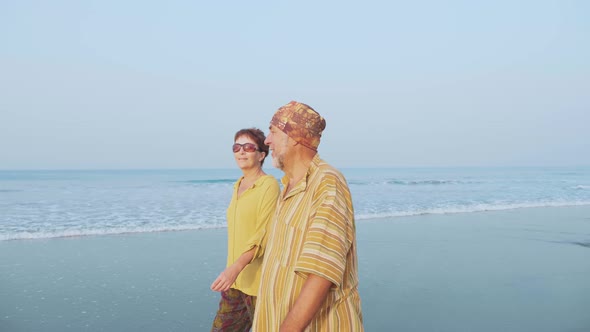 Senior couple walking on the beach and talking, steadicam shot