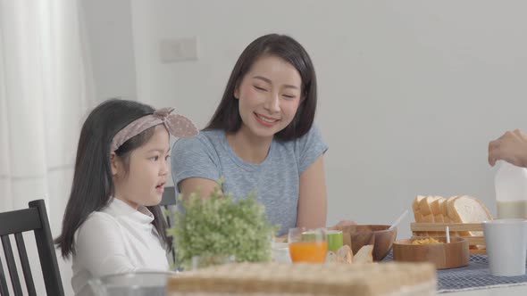 Parent and daughter eating Cereals with milk having breakfast morning in kitchen.