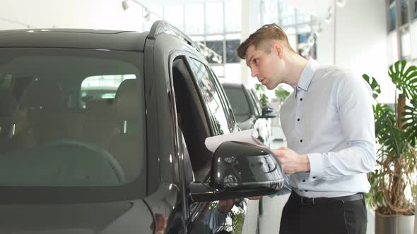 A Car Dealership Employee Inspects the Car To Describe the Set-up